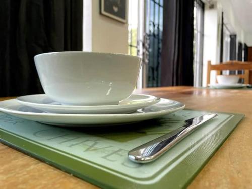 a white cup and plate on a table with a spoon at Spring Valley Vista, Ocean View Apartment Ocho Rios in Tower Isle