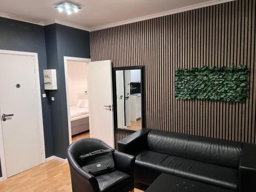 a living room with a black leather couch and a mirror at HPI Apartments in Aarhus