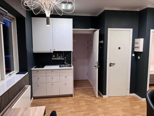 a kitchen with white cabinets and a black wall at HPI Apartments in Aarhus