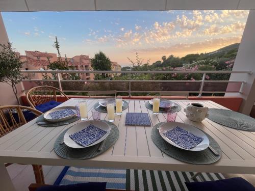 une table avec des assiettes et de la vaisselle sur un balcon dans l'établissement Appartement Marinella route des Sanguinaires Corse, à Ajaccio