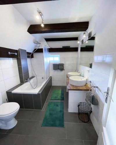 a bathroom with two sinks and a tub and a toilet at Pauerhof Ferienwohnungen in Bad Nenndorf