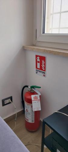 a room with a fire extinguisher sign and a red container at Casa Amare Aeroporto Fiumicino in Focene