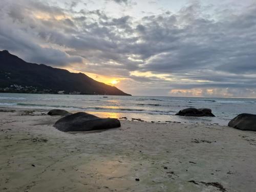 a sunset on a beach with rocks in the sand at Tropical Secrets Holiday Apartments in Victoria