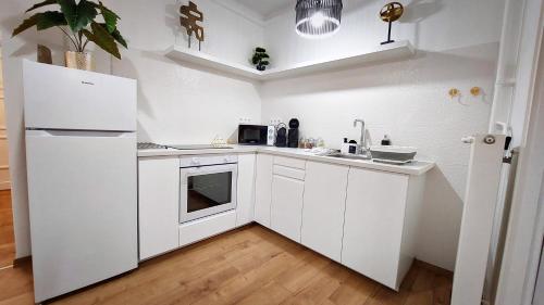 a kitchen with white cabinets and a white refrigerator at Central Station Lux Downtown Apartman in Budapest
