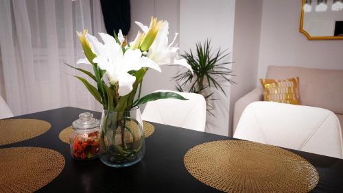 a glass vase with white flowers on a table at Central Station Lux Downtown Apartman in Budapest