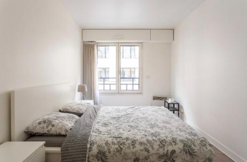 a white bedroom with a bed and a window at Appartement champ elysee in Neuilly-sur-Seine