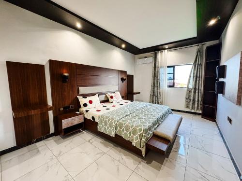 a bedroom with a large bed with a wooden headboard at Novel Apartments in Limbe