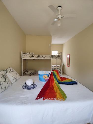 a white bed with a colorful blanket on it at Suítes Córdoba SP in Bertioga