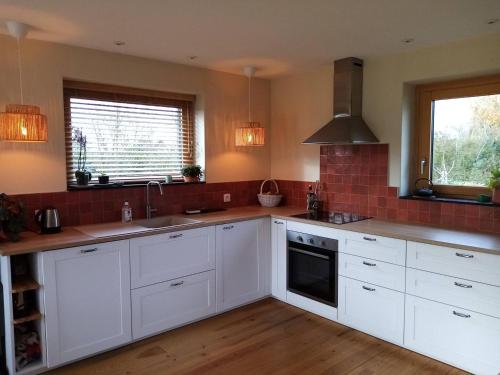 une cuisine avec des armoires blanches et un évier dans l'établissement Maison en bois à la campagne proche vilaine, à Férel