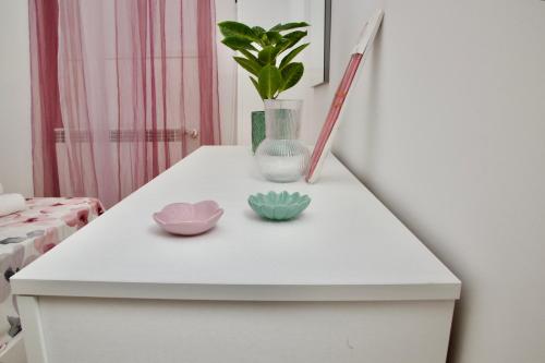 a white table with two bowls and a vase on it at Casa Amare Aeroporto Fiumicino in Focene