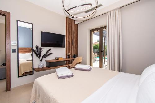 a bedroom with a white bed and a large mirror at Nestor Luxury Villas in Romanu