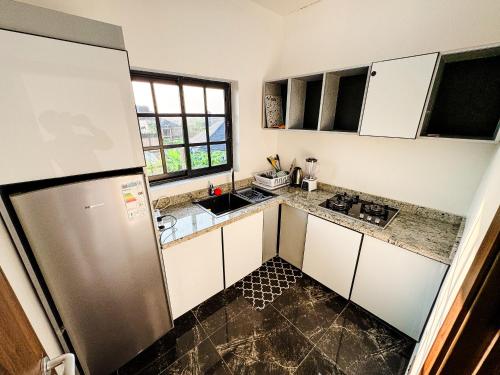 a kitchen with white cabinets and a stainless steel refrigerator at Novel Apartments in Limbe