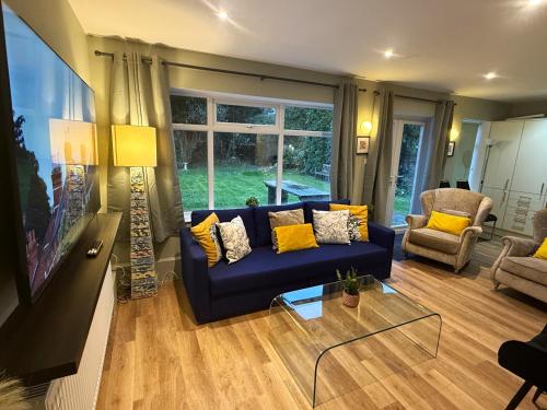 a living room with a blue couch and yellow pillows at Bicester villa, 5Bedroom, Parking, WiFi, Garden in Bicester