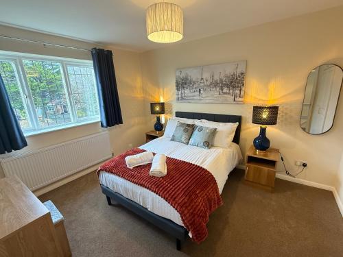 a bedroom with a bed with a red blanket and two lamps at Bicester villa, 5Bedroom, Parking, WiFi, Garden in Bicester