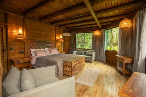 ein Schlafzimmer mit einem Bett und einer Couch in einem Zimmer in der Unterkunft Grajagan Mata Atlântica in Antonina