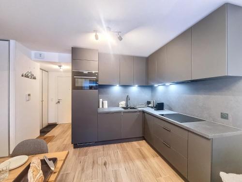 une cuisine avec des appareils en acier inoxydable et une table dans l'établissement Le Cherry- appartement-4Pers-Proche Centre, aux Gets