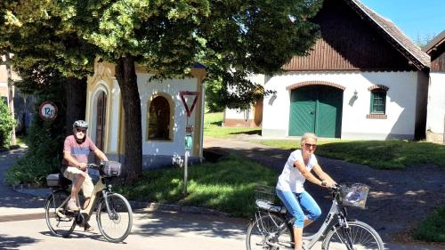 two people riding bikes down a street at FERIENHAUS Weinviertel in Pernersdorf