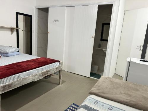 a bedroom with a bed and a bathroom with a mirror at Pousada Quintal Verde Floripa in Florianópolis