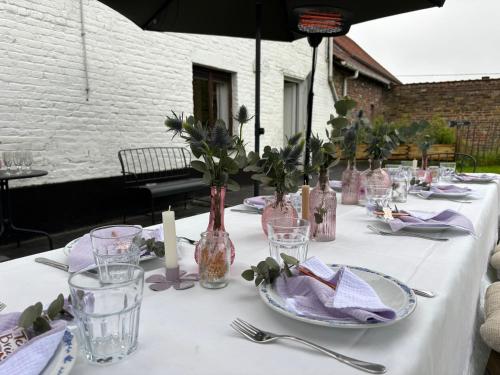 a table with a white table cloth with glasses and vases at Vakantiewoning Wurfeldermolen in Maaseik