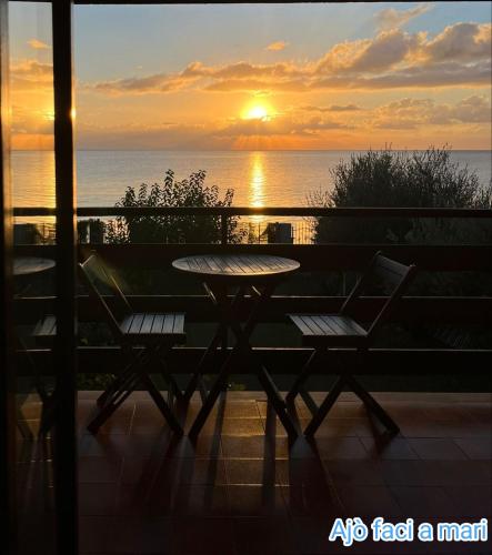 a table and chairs on a balcony with a sunset at Ajò Faci a Mari in Capoterra