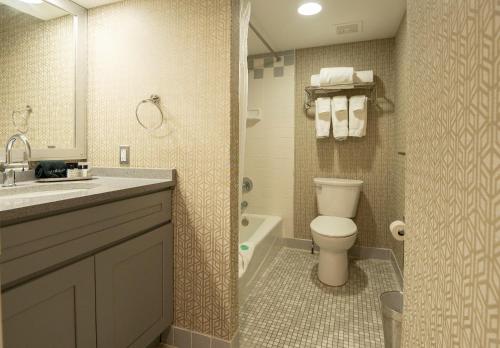 a bathroom with a toilet and a sink and a tub at The Americus Hotel, Trademark Collection by Wyndham in Allentown