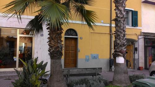 two palm trees in front of a building with a wooden door at Appartamento Torrione in Piani di Vallecrosia