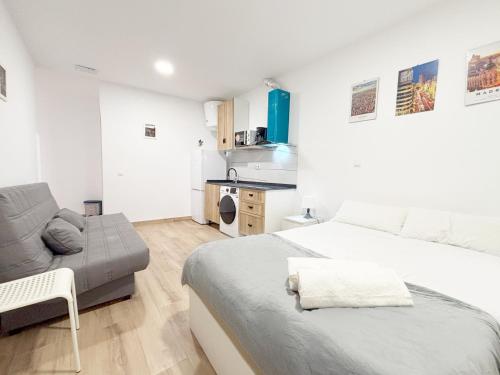a white bedroom with a bed and a couch at Nuevo, luminoso y céntrico in Madrid