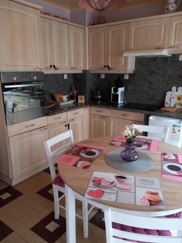 - une cuisine avec une table en bois, des chaises et un four dans l'établissement Chez Sabine et Sarah, à Gacé