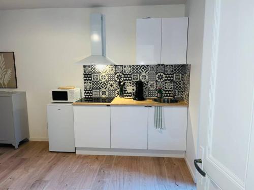 una cucina con mobili bianchi e pavimento in legno di Henri ll l Terrasse l Proche gare & Centre ville a Castres