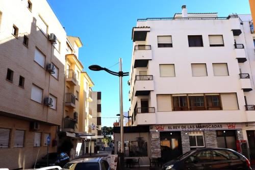 a tall white building with cars parked on a street at Los Pescadores playa LEK in Peñíscola