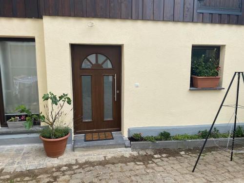 una casa con una porta marrone e due piante in vaso di Ferienwohnung Eschbach Hof 2 am Nürburgring a Herresbach