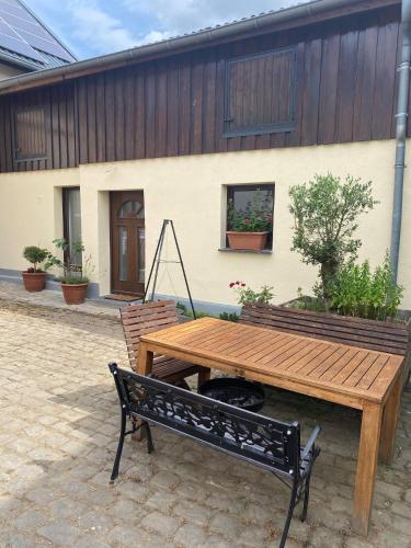 un tavolo in legno e una panca di fronte a un edificio di Ferienwohnung Eschbach Hof 2 am Nürburgring a Herresbach