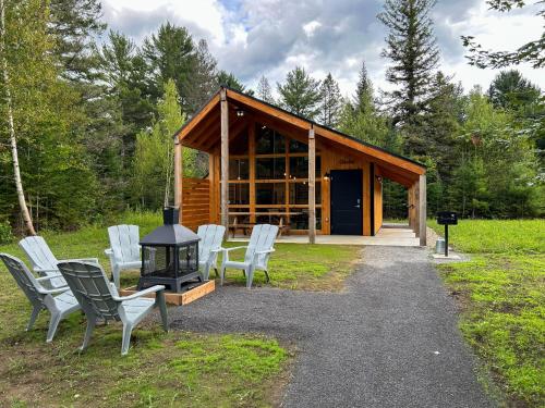 a cabin with white chairs and a wood stove at Chalets Lanaudière in Rawdon