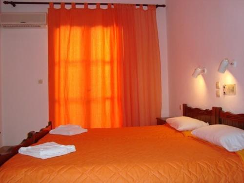 a bedroom with two beds and an orange curtain at Hotel Elida in Platanes