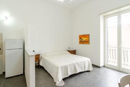 a white bedroom with a bed and a refrigerator at Dimora Borbonica in Ercolano