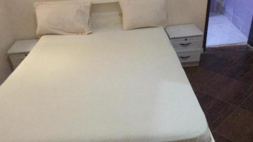 a white bed with two pillows on top of it at darou salam house in Rufisque