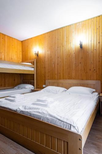 a large bed in a room with wooden walls at Готельний комплекс Парламент, Яблуниця in Yablunytsya