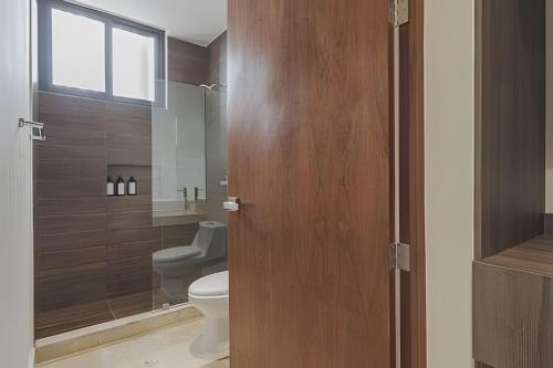 a bathroom with a toilet and a wooden door at Zirene, Depto con jacuzzi priv in Chicxulub