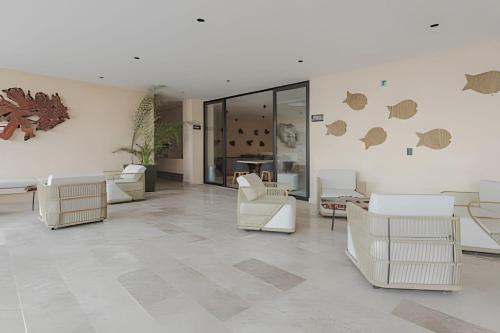 a living room with white furniture and a wall with art at Zirene, Depto con jacuzzi priv in Chicxulub