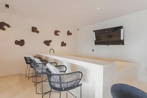 a bar with chairs and a television on a wall at Zirene, Depto con jacuzzi priv in Chicxulub