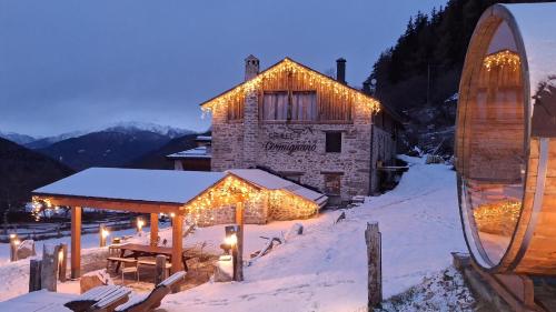 a building covered in christmas lights in the snow at Chalet Cormignano in Vezza dʼOglio