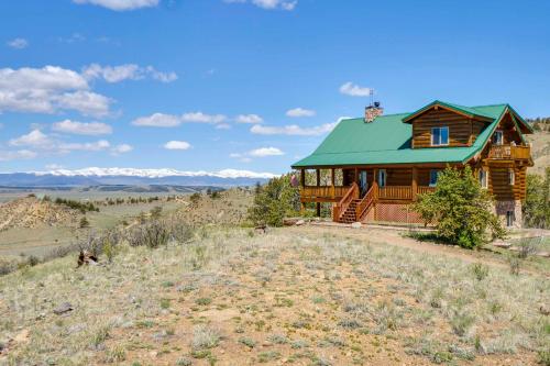 a log cabin with a green roof on a hill at 24-0089 Rustic Hartsel Getaway with 35-Acre Yard in Fairplay