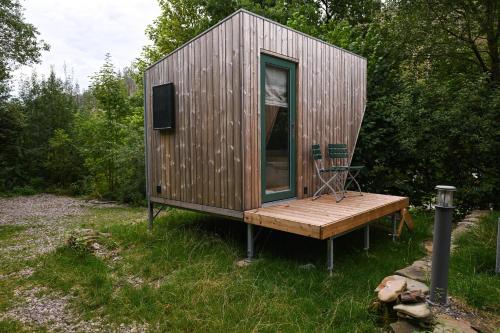 a small wooden cabin with a bench in the grass at Green Tiny Village Harz - Sleep Space 32 in Osterode