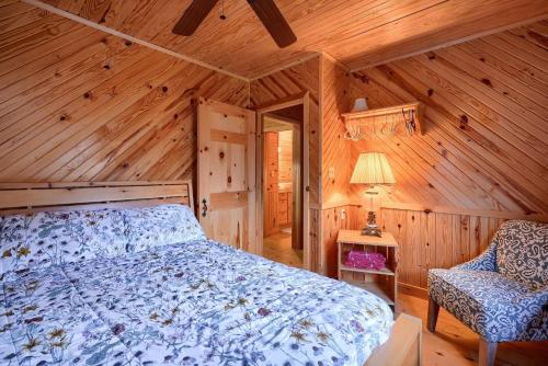 a bedroom with a bed and a chair in a cabin at Bison Hollow Hideaway in South Bloomingville