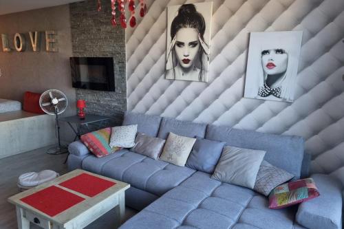 - un salon avec un canapé bleu et 2 peintures dans l'établissement Naturiste Cap d'Agde Héliopolis C 65, au Cap d'Agde