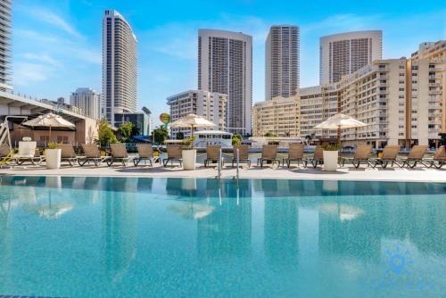 a swimming pool with chairs and umbrellas in a city at Amazing Studio with Balcony & Pool in Hallandale Beach