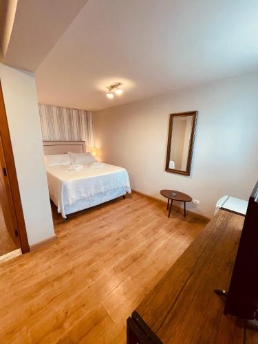 a bedroom with a white bed and a wooden floor at Pousada Cantinho da Serra in Campos do Jordão