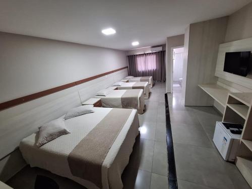 a row of beds in a room with a tv at Hotel Descanso in Descanso