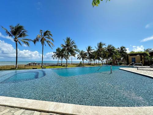 une piscine avec des palmiers et l'océan dans l'établissement Casa Vista Mar de Luxo com Serviços Inclusos, à Barra do Camaragibe
