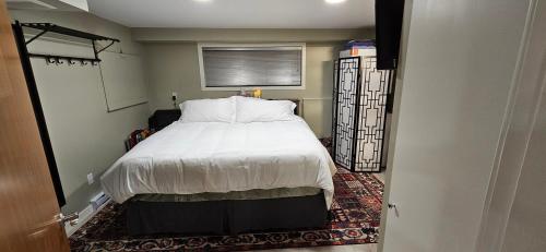 a bedroom with a bed with white sheets and a window at 1 block to Kelowna General Hospital 2 blocks to Beach 1km to OUC 1km to Downtown Kelowna 20min to YLW in Kelowna